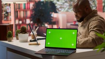 Startup administrator calculates economic budget balance at his home office, using isolated chroma key green screen. Entrepreneur reviews monthly sales reports, investment funds. Camera A. photo