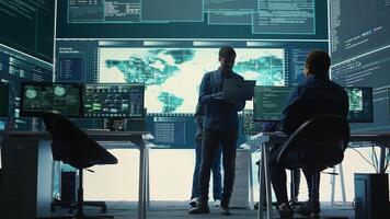 Governmental hackers performing a cyber attack simulation after studying the national database servers. Experts working on IT security, data breach prevention against ransomware. Camera B. photo