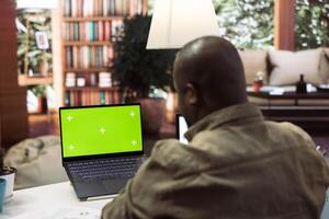 Businessman reviewing statistics reports next to an isolated mockup screen at home office, adviser calculating budget in order to expand the enterprise activity. Finance and economy. photo