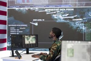 Team of military soldiers operate advanced computers and a big screen in a monitoring room, managing surveillance and data analysis. Mission control center staff work with cctv radar footage. photo