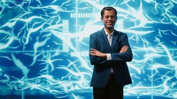 Smiling technician in startup stands with arms crossed, exuding professionalism and expertise. Portrait of cheerful Indian IT expert working in futuristic artificial intelligence workspace, camera A photo