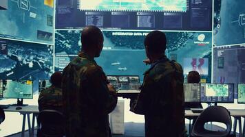 Intelligence analysts supervising and coordinating the big data analysis, processing tactical information to help the field troops. Officers monitoring real time warfare information. Camera B. photo