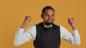 Waiter flexing his muscles and showing his strength in studio, acting tough while he wears his restaurant uniform and apron. Professional employee in service oriented industry. Camera A. photo