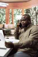Entrepreneur sharing office space layout ideas with designers on phone call, planning a building renovation for the new creative workspace. Using architectural blueprints for a modern layout. photo