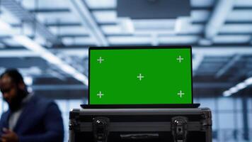 Green screen laptop used by engineers monitoring server room, doing checkup. Focus on chroma key notebook used by IT support employee working in data center facility, camera A close up photo