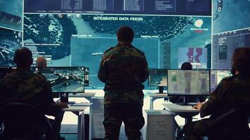Woman colonel handling a special operation with big data in monitoring room, providing important satellite information to her crew in command post. Targeting enemy power base. Camera B. photo