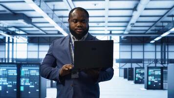 IT engineer working on laptop in modern data center, overseeing server operations, system maintenance,and cybersecurity protocols, ensuring optimal performance and data integrity, camera A photo