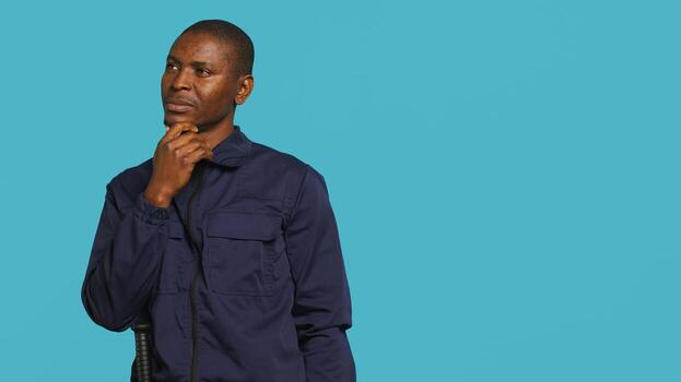 Security guard doing thinking hand gesture, being tasked with preventing criminal activity and detaining suspects. Portrait of pensive bodyguard rubbing chin, studio background, camera A photo