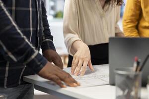 Realtor helping her clients with potential investment in property, evaluating architectural plans of the modern building layout. Business people planning an office relocation. Close up. photo