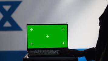 Israel secret police agent uses mass propaganda tools on green screen laptop to influence population minds and spread misinformation. Mossad spy commits PsyOp sabotage using mockup notebook, camera A photo