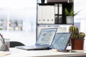 Laptop device on office desk in empty workspace showing volatile stock exchange prices going up and down. Brokerage firm with forex trading platforms indexes on notebook screen photo