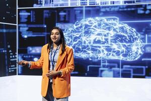 Smiling IT specialist holding presentation exploring ways emerging AI technologies can enhance companies workforce. Indian woman at event presents strategies for using artificial intelligence photo
