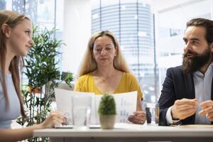 Financial advisor discussing with customers, presenting informational materials and recommending optimal insurance policies. Agent informing clients of investment options, showing them charts photo