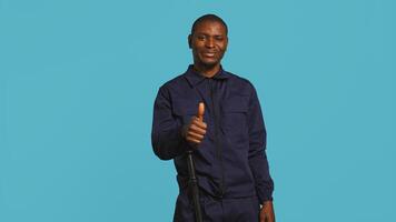 Happy security guard doing thumbs up sign gesturing with finger, preventing public access in restricted area. Portrait of smiling bodyguard doing positive hand gesture, studio background, camera B photo