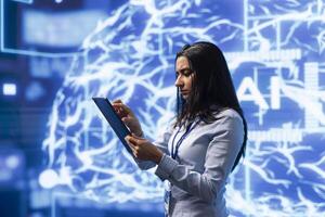 Computer scientist using artificial intelligence computing simulating human brain thought processes. Indian employee working on tablet, developing AI machine learning algorithms photo