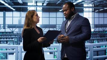 Team of admin in server hub check recovery plan, monitoring data center energy consumption across components. Coworkers ensures sensors are functioning optimally, doing routine disk checks, camera A photo