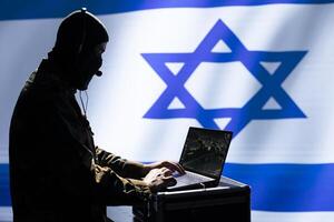 Israeli espionage division officer using reconnaissance software on laptop to detect enemy location. Incognito Mossad agent in control room isolated over Israel flag using satellite gadget photo