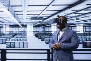 Programmer in server hub using VR headset to implement and maintain security measures, protecting systems from unauthorized access. Data center employee does hardware maintenance using virtual reality photo
