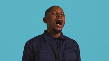 Portrait of security job employee yawning while at work detaining perpetrators, feeling tired. Patrol guard feeling exhausted after long night shift, isolated over studio background, camera B photo