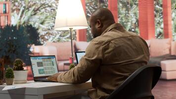 General manager examines financial reports and performance metrics to assess expansion plans from his home office. Business consultant reviews online infographics, balance and expenses. Camera A. photo