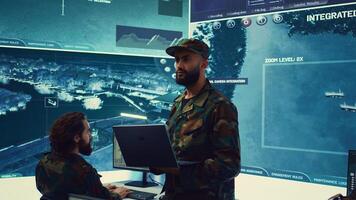 Army general managing air traffic control for military aircraft within the operational area, uses radar surveillance. Follows vessels on navy reconnaissance satellite system, big screen. Camera B. photo