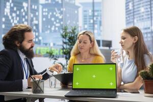 Financial advisor presenting financial guide to customers using green screen laptop. Agent in office assisting clients with investment portfolio management helped by chroma key notebook photo