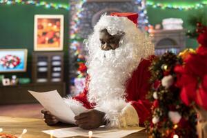 Santa Claus checking a letter while sitting in his rustic festive cabin, fulfilling wishes for children around the world. Saint Nicholas prepares gifts and toys for the winter holiday journey. photo