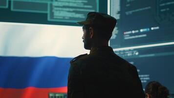 Military hacker from Russian army working in governmental control room cracking rival states network systems to spread fake news and hybrid war propaganda. Brainwashing ideology strategy. Camera A. photo
