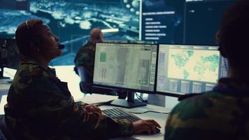 Woman army officer operates on gps surveillance footage to gather crucial information about enemy plans. Operator examines a satellite world map to provide support to field troops. Camera B. photo