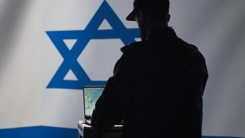 Iranian conscript in control room uses military tech to identify threats from enemies. Iran IDF army operator uses software on laptop to communicate information to generals on war front line, camera A photo