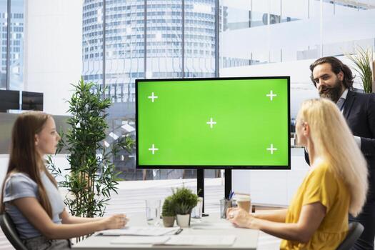 Broker in office offering financial advice to clients, looking at forex index values on green screen display. Financial advisor analyzing customers market shares on chroma key device photo