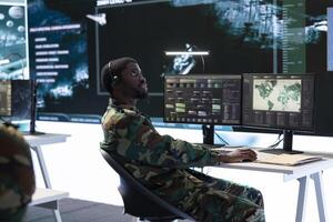 Army officer working with modern computer systems and satellite data for surveillance operations, gather intelligence to protect national interests. Strategic planning in a high tech base. photo