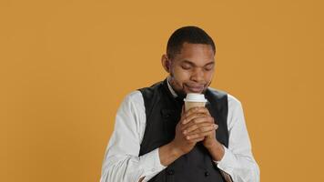 Cheerful waiter drinking a cup of coffee and relaxing after serving clients, working in catering and service oriented industry. Restaurant staff enjoying a caffeine refreshment. Camera A. photo