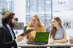Family receiving personalized financial plan from financial advisor using green screen laptop during meeting. Clients learn how to make profitable decisions from agent using mockup notebook photo