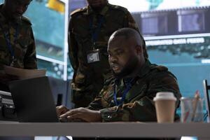 Soldiers analyzing and collecting real time data in a high tech military office, working on intelligence gathering for successful defense operation. Ensure military objectives for protection. photo