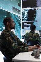 Army intelligence specialists utilize advanced computer systems, surveillance technology and satellite data to enhance national security. Working in a command post against potential threats. photo