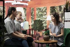 In a confidential therapy session teenage girl and her mother discuss personal troubles and emotional struggles. The therapist provides guidance for navigating adolescence and behavioral therapy. photo
