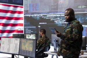 US military personnel work in a modern army command post, safeguarding classified information and state secrets against cyber attacks. Managing digital warfare and cybersecurity operations. photo
