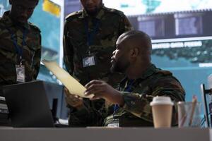 Team of army officers collecting satellite data and live information, coordinating strategic missions to support new field operation for national defense. High tech military drone control. photo