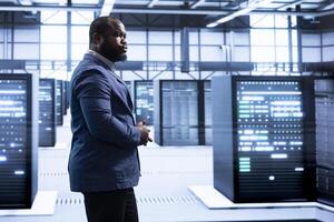 Supervisor overseeing server room, implementing and maintaining security measures, protecting systems from unauthorized access. Professional walks in data center workspace, doing hardware maintenance photo
