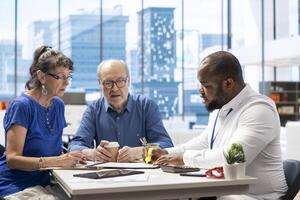 Elderly couple discussing about retirement plans with a financial planner, covering savings strategy and pension options. Middle aged people looking to invest to secure their budget. photo