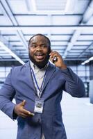 Manager talking on smartphone in high tech data center housing advanced computing gear. Specialist delegating tasks in technologically advanced server hub during telephone call photo