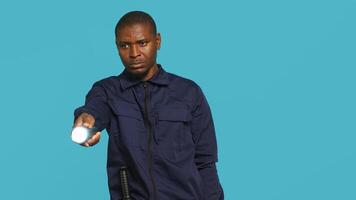 Security guard turning on flashlight, being tasked with preventing criminal activity and detaining suspects performing crimes. Portrait of bodyguard using lantern device, studio background, camera A photo