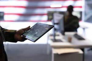 Team of military experts operates high tech computers and tablet to analyze surveillance data and manage national security operations. Working with CCTV radar satellite imagery. Close up. photo