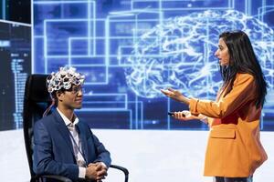 Presenter talking at AI neuroscience forum bringing together IT professionals, showing EEH headset demonstration of latest developments in artificial intelligence mind transfer photo