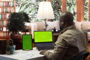 Business owner works from his home with isolated mockup screen and annual data reports for the financial situation. Entrepreneur examines profit numbers for performance metrics. photo