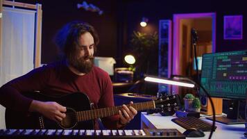 Portrait of artist recording tunes on daw software with his guitar, enjoying time in his home studio office. Audio engineer and musician creating new tracks, stereo electronic instruments. Camera B. photo