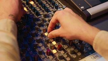 Audio technician twisting pre amp knobs and buttons on panel board in control room, using editing console for mixing and mastering tracks. Professional tracking engineer in music studio. Camera A. photo