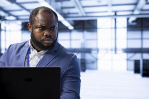 Engineer in data center using tools on laptop designed to handle challenges of managing cloud and distributed infrastructure. Expert planning and executing server hub migrations and upgrades photo