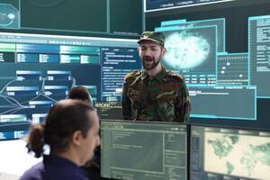 Military soldier working in a government cyber defense agency office with big screen, cyber attack prevention. Army hackers team securing sensitive data from spyware and malware threats. photo